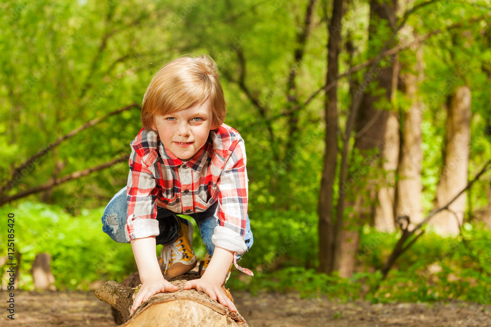 Portrait of blond young boy standing on a log