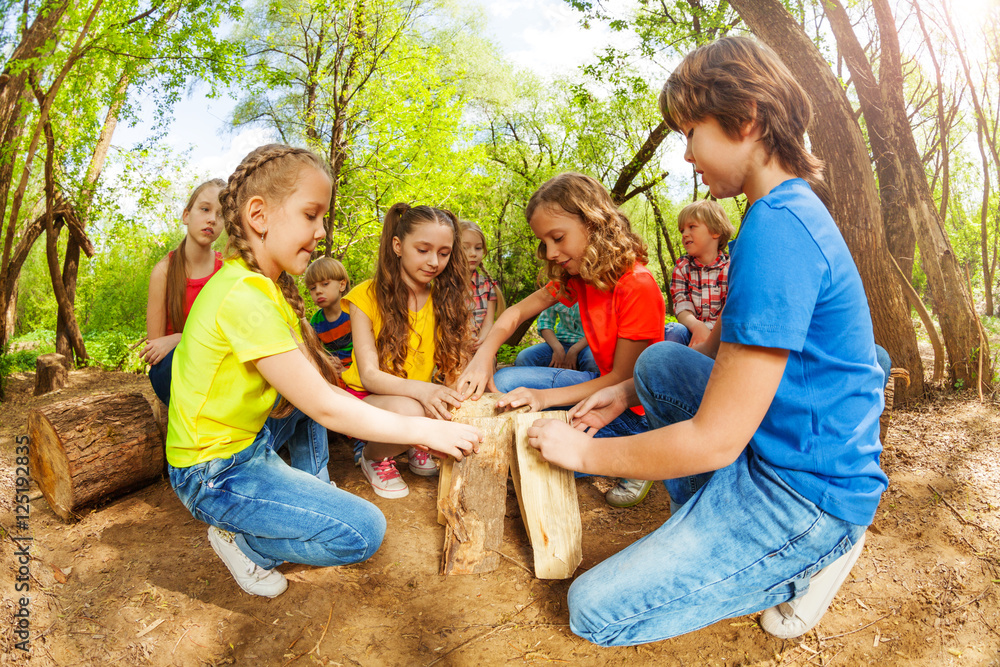 Happy children playing with logs in the forest