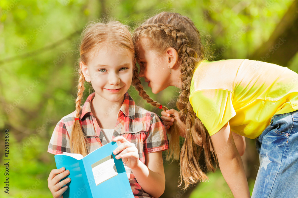 Two little girls whispering secrets in the ear