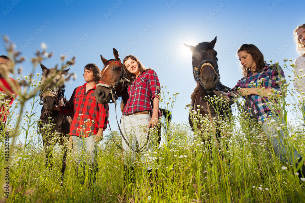 Outdoor portrait of young people with their horses