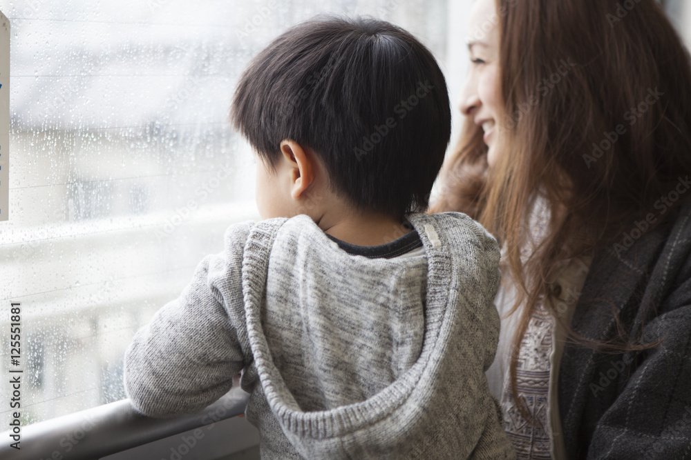 Mother and son are watching the rain