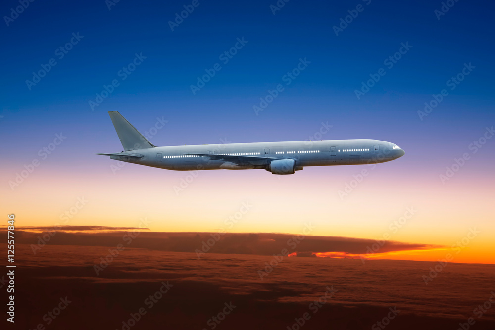 Airplane flying high above the clouds at sunset .