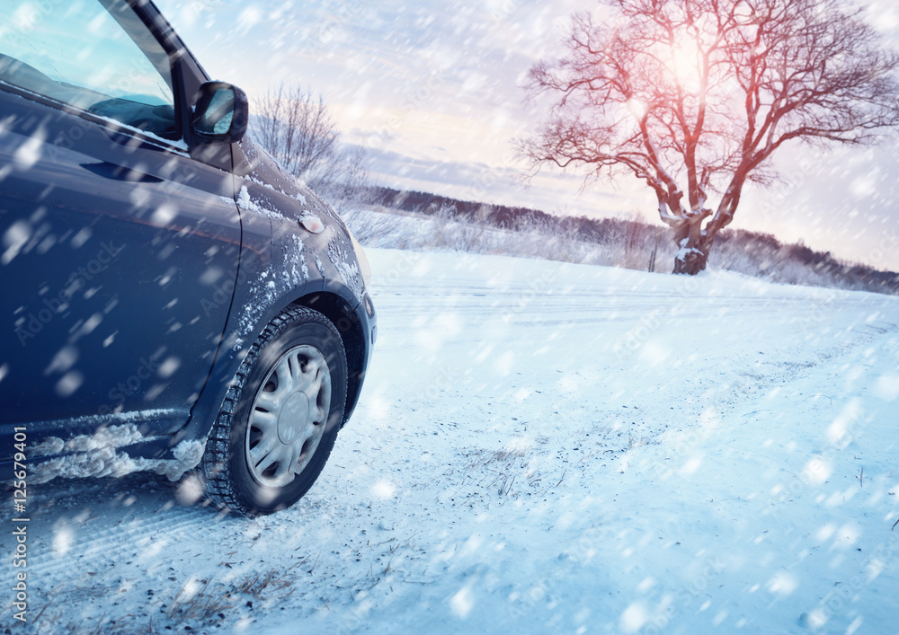 冬季道路上的汽车轮胎被雪覆盖。早上下雪时，车辆在雪地小巷上行驶