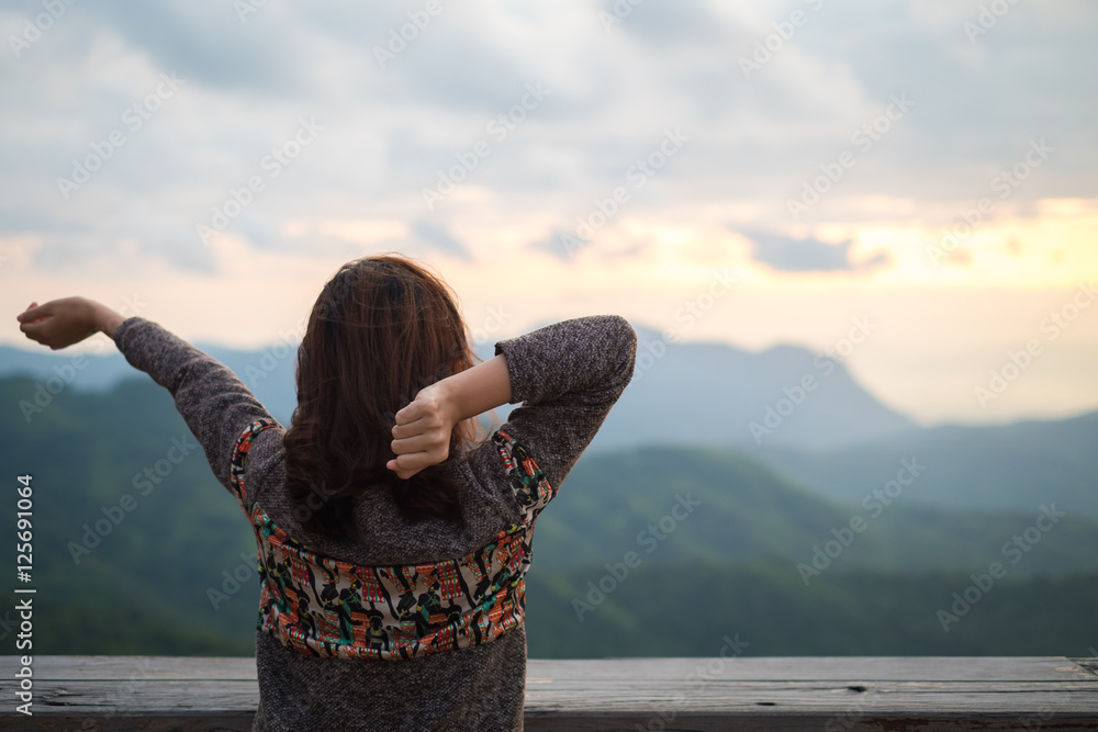 Young woman stretching on balcony with mountain view in early winter morning.