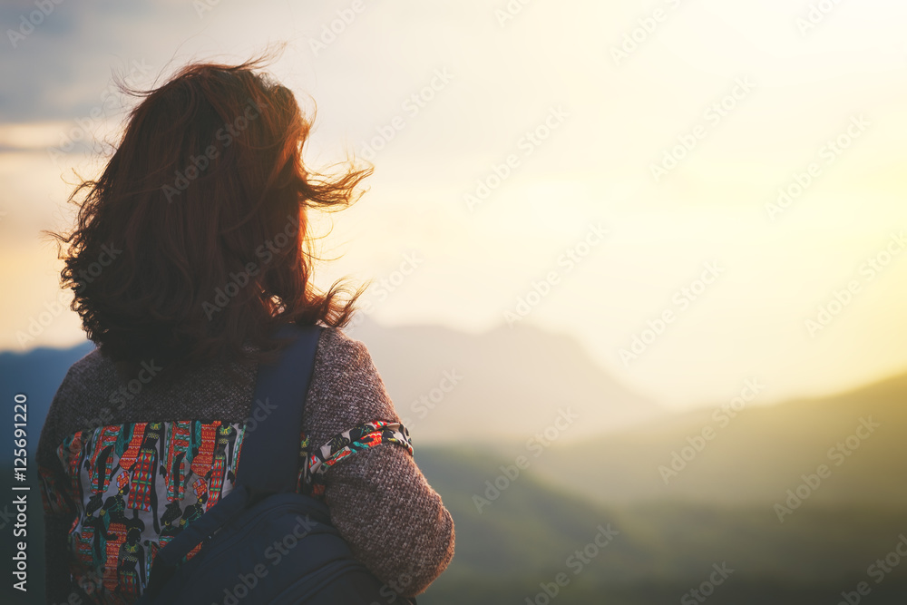 背着背包的时髦年轻女子在山上欣赏日出