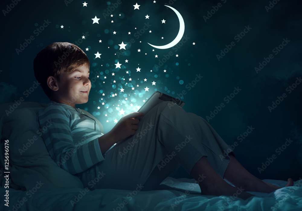 Boy with tablet in his bed