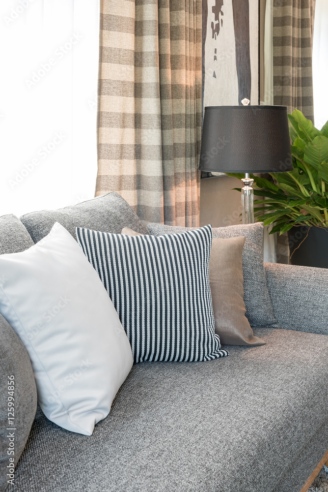 row of pillows on grey sofa with black lamp in living room