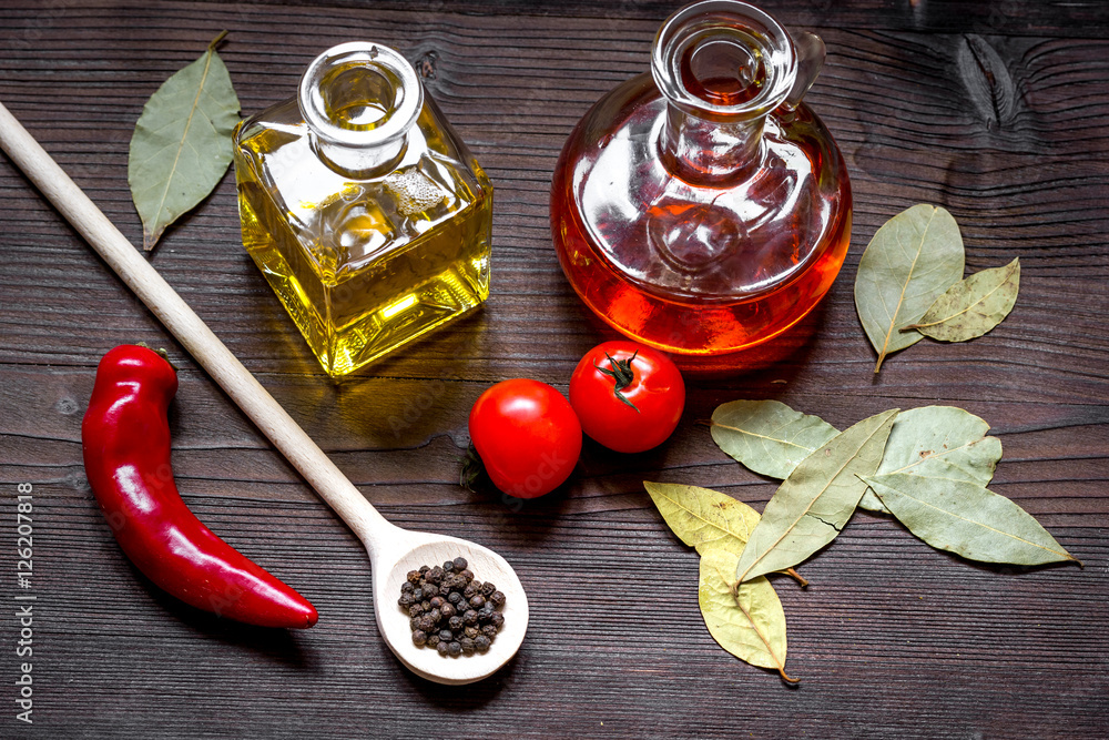 carafes with oil and tomatoes on wooden background