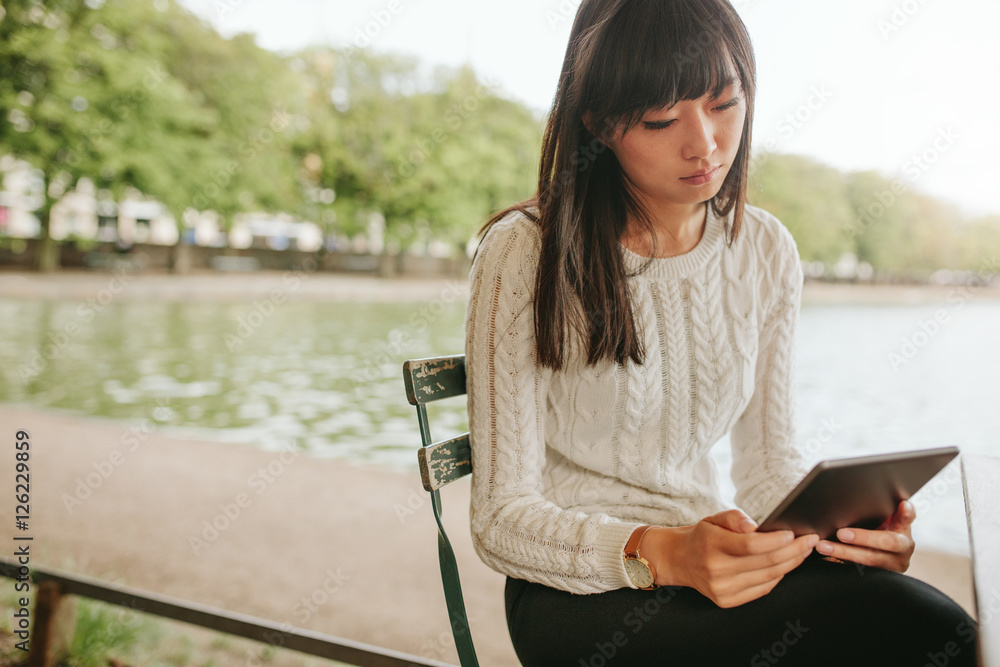 年轻女子拿着数字平板电脑坐在咖啡馆