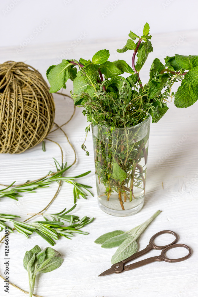 Fresh herbs in glass on wooden background