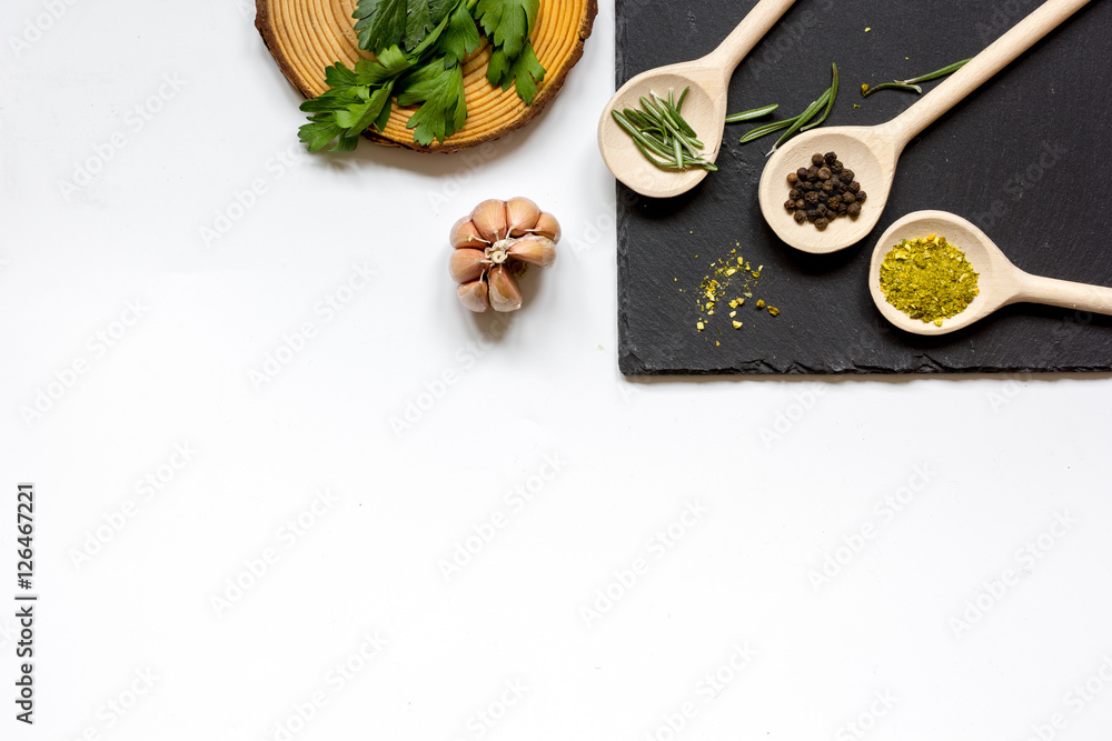 various spices in wooden spoons on white background top view