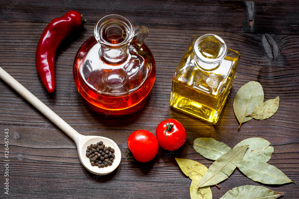 carafes with oil and tomatoes on wooden background