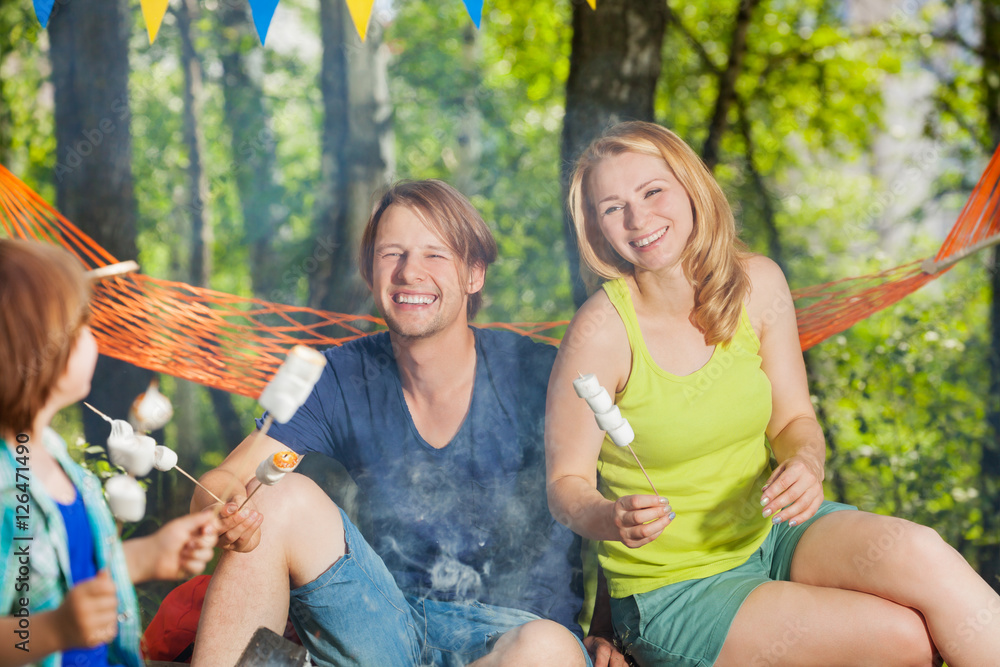 Happy smiling family roasting shmallows outside