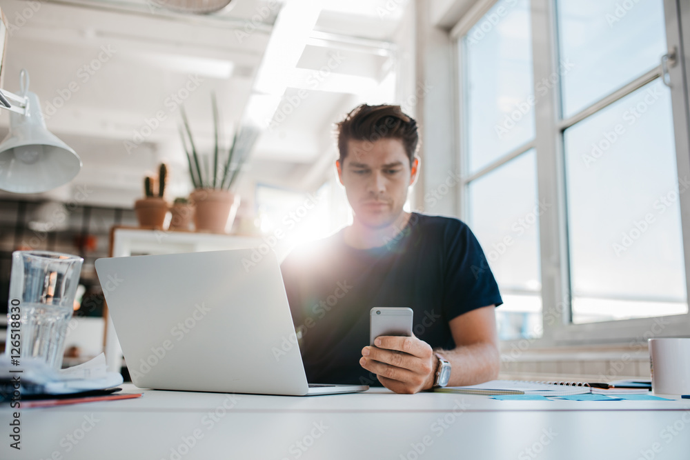 Businessman reading text message on his mobile phone.