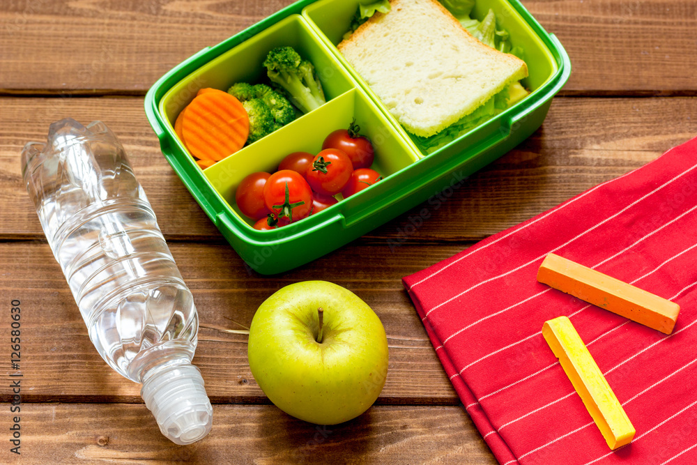 lunch box for kid with fresh vegetables on wooden background