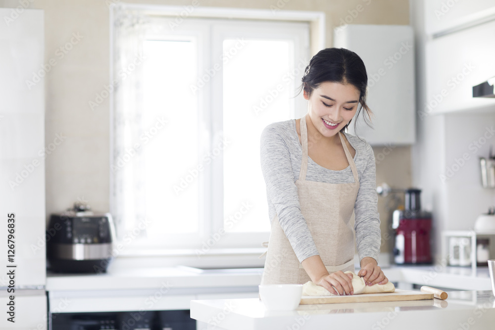 Young woman kneading dough on cutting board