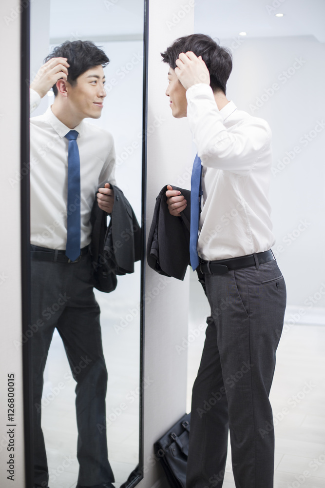 Young man examining himself in front of mirror