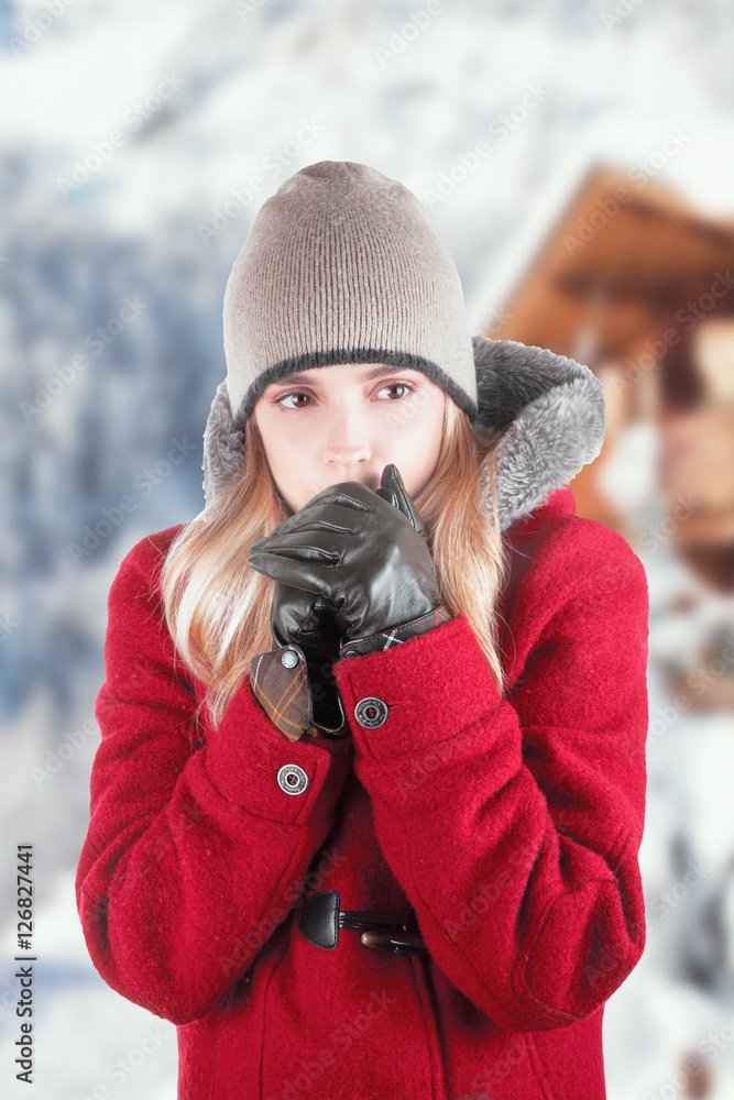 Donna in montagna con cappotto si scalda le mani con guanti e cappello 