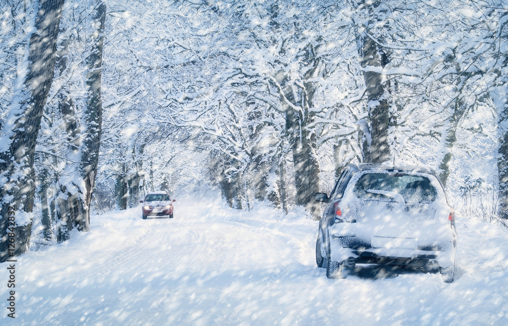 冬季道路上的汽车轮胎被雪覆盖。早上下雪时，车辆在雪地小巷上行驶