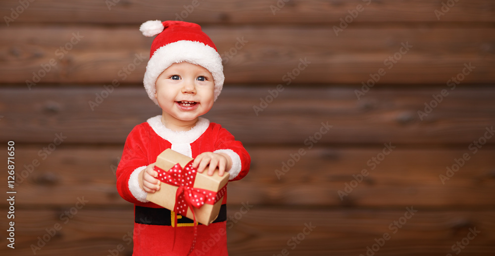 Happy baby in a Christmas costume Santa Claus with gifts