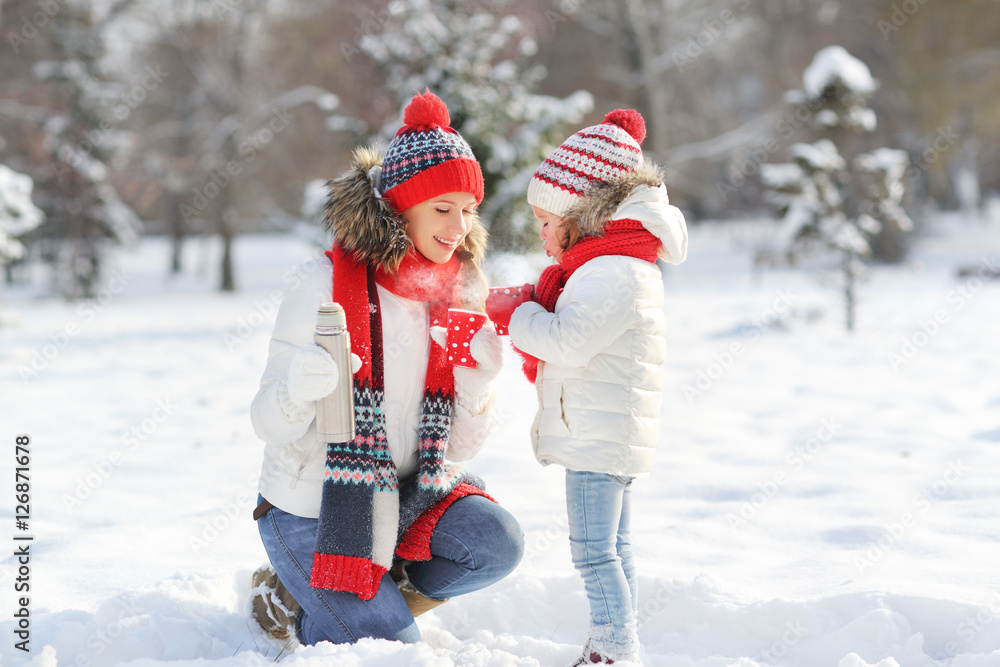 happy family mother and child on winter walk drinking tea