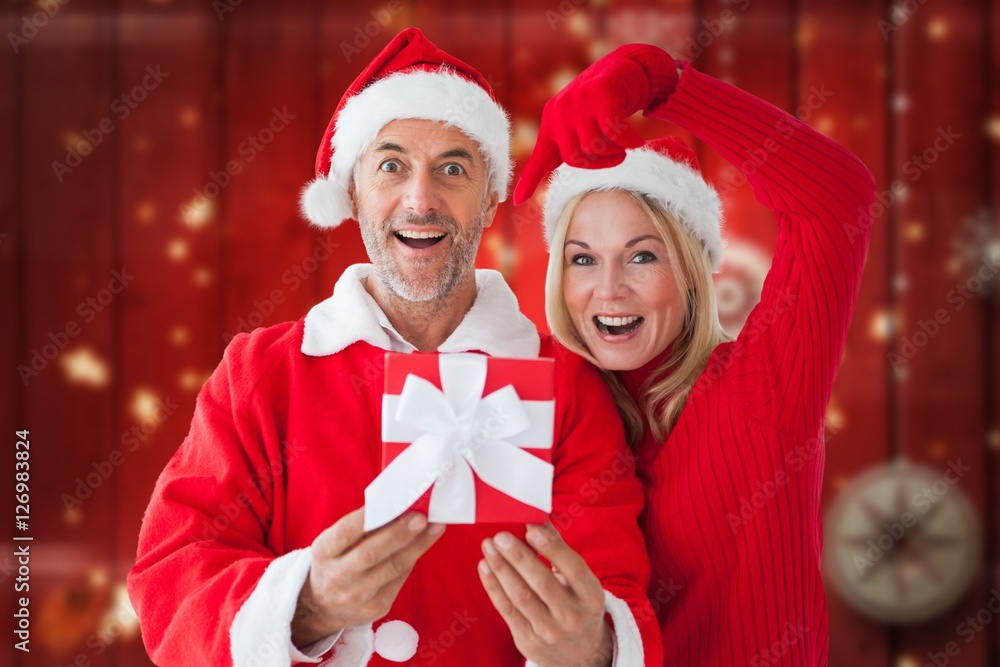 Portrait of happy couple in santa costume holding christmas gift