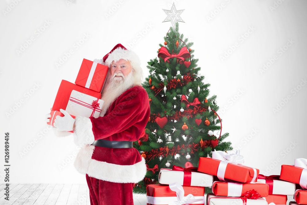 Santa claus holding stack of gift boxes near christmas tree