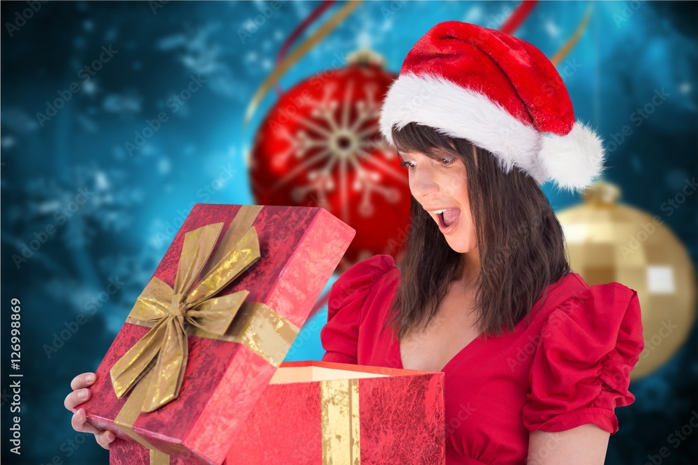 Surprised woman in santa hat looking at christmas gifts