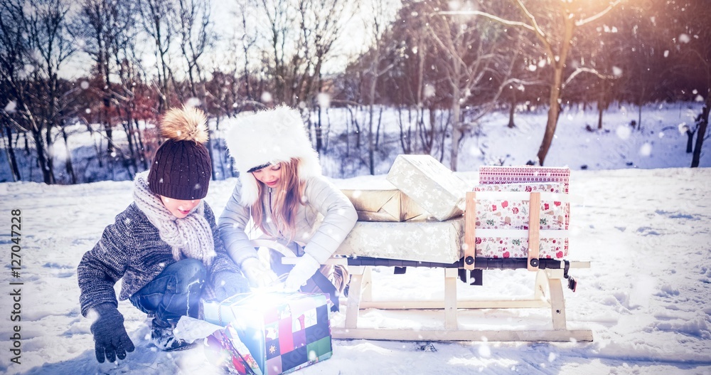 Composite image of brother and sister opening present by sledge 