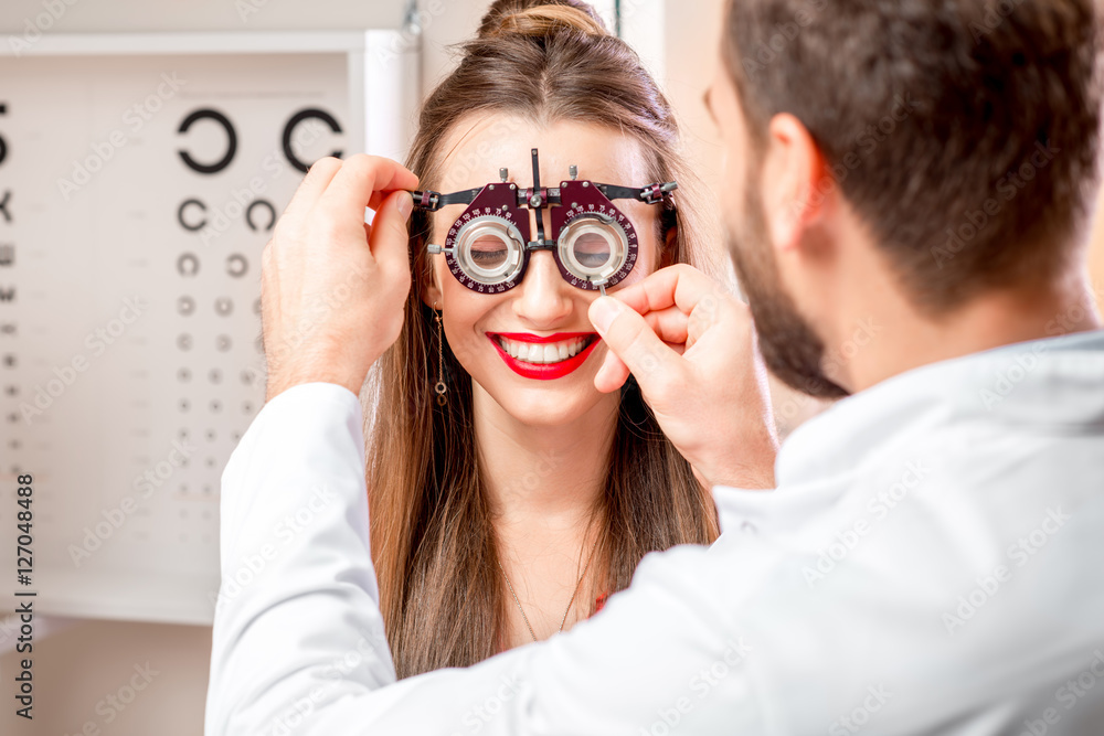 Ophthalmologist wearing try-on tool for vision check to the young female patient in front of the eye