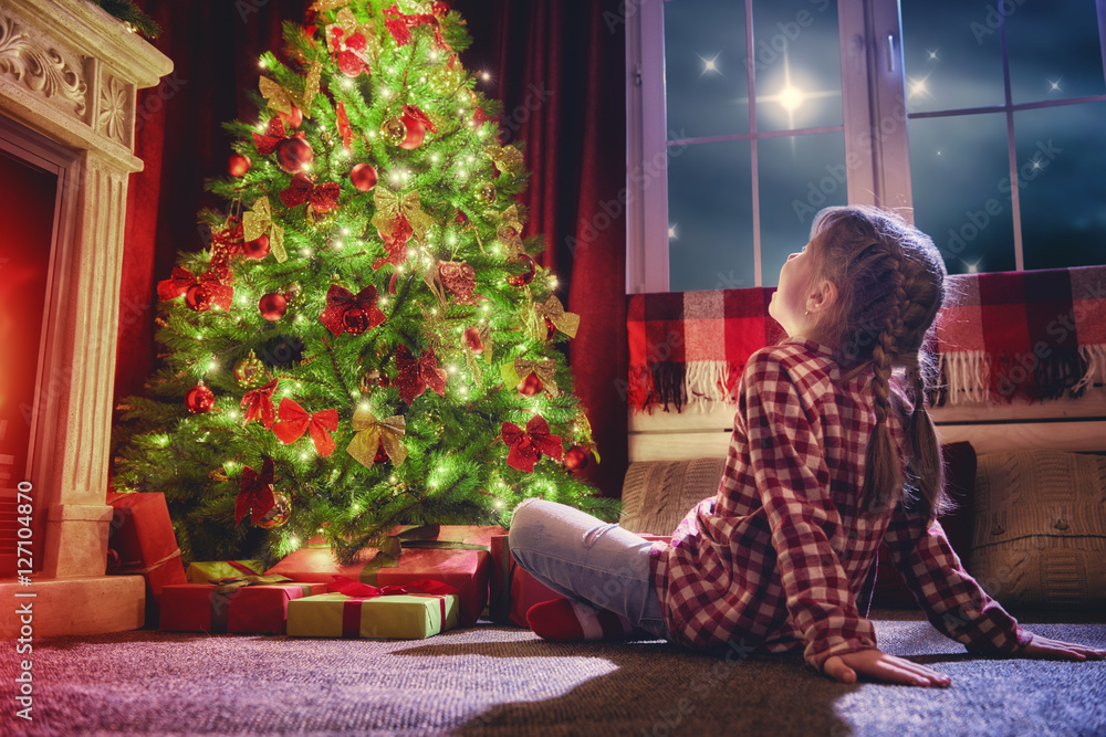 girl looking at decorations the Christmas tree.