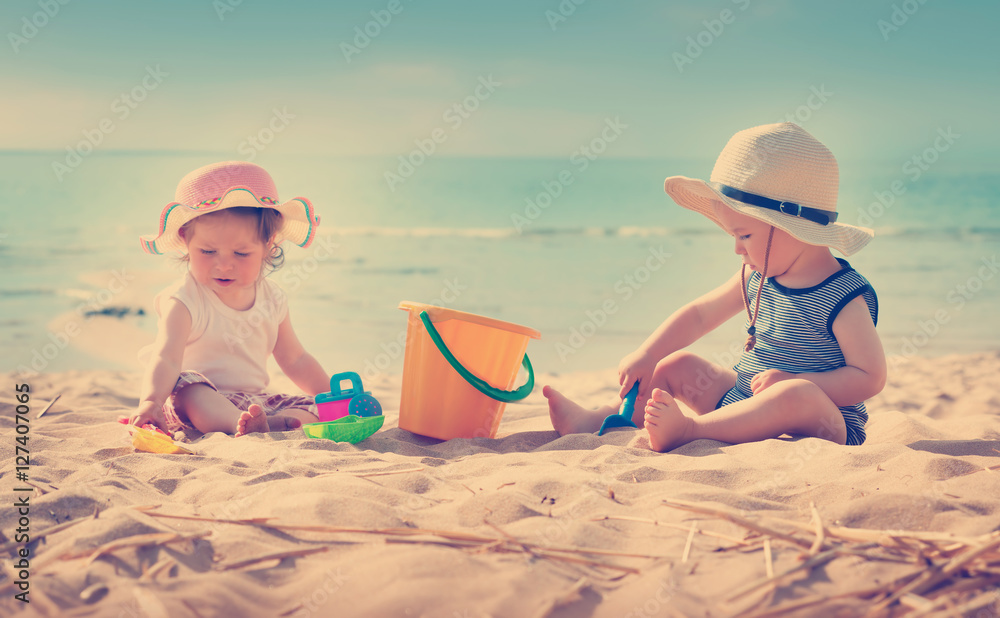 Babygirl and babyboy sitting on the beach