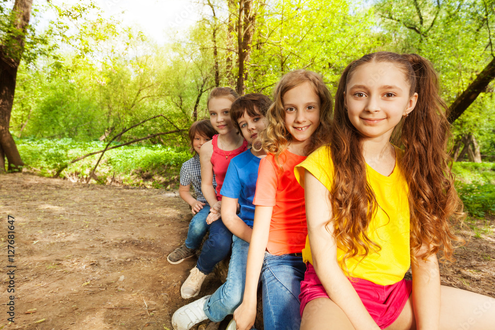 Cute happy kids sitting on a log in the forest