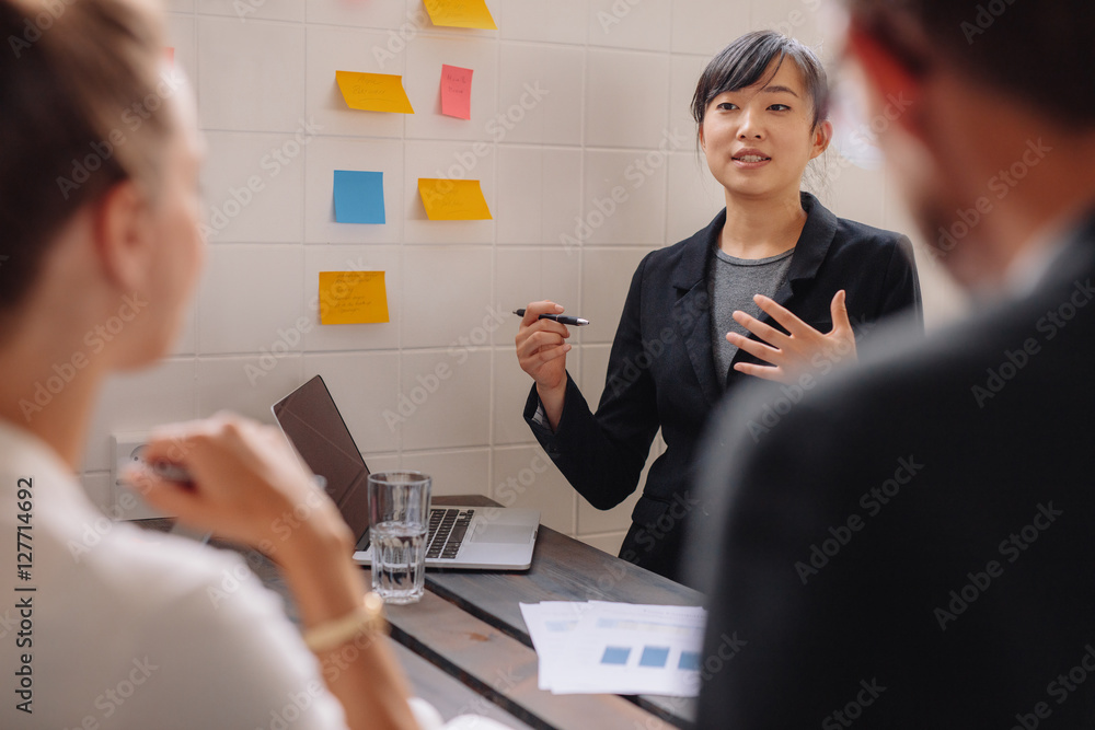 Young female executive giving presentation to colleagues