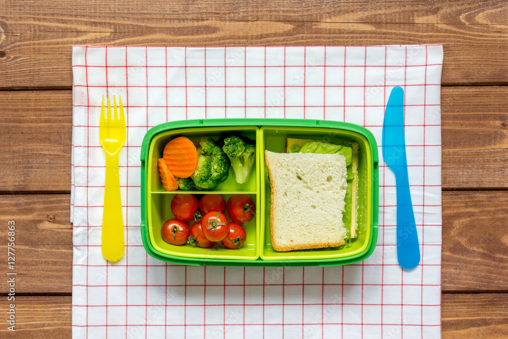 green lunch box for kid on wooden background top view