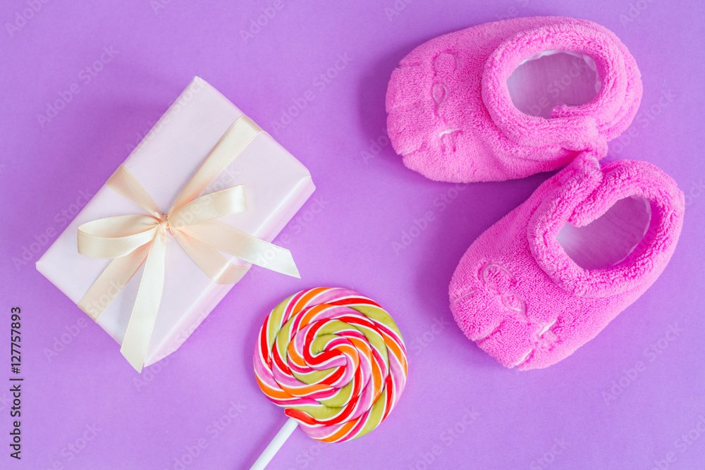 babys bootees and gift box on purple background