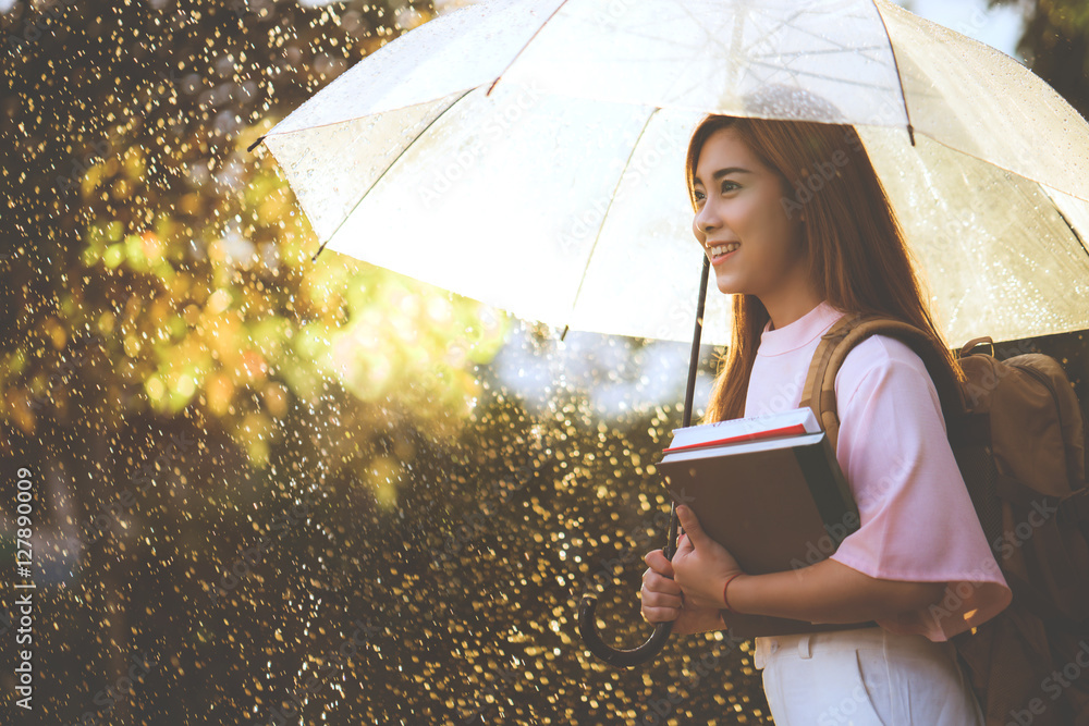 亚洲学生在等雨，她有一把伞。