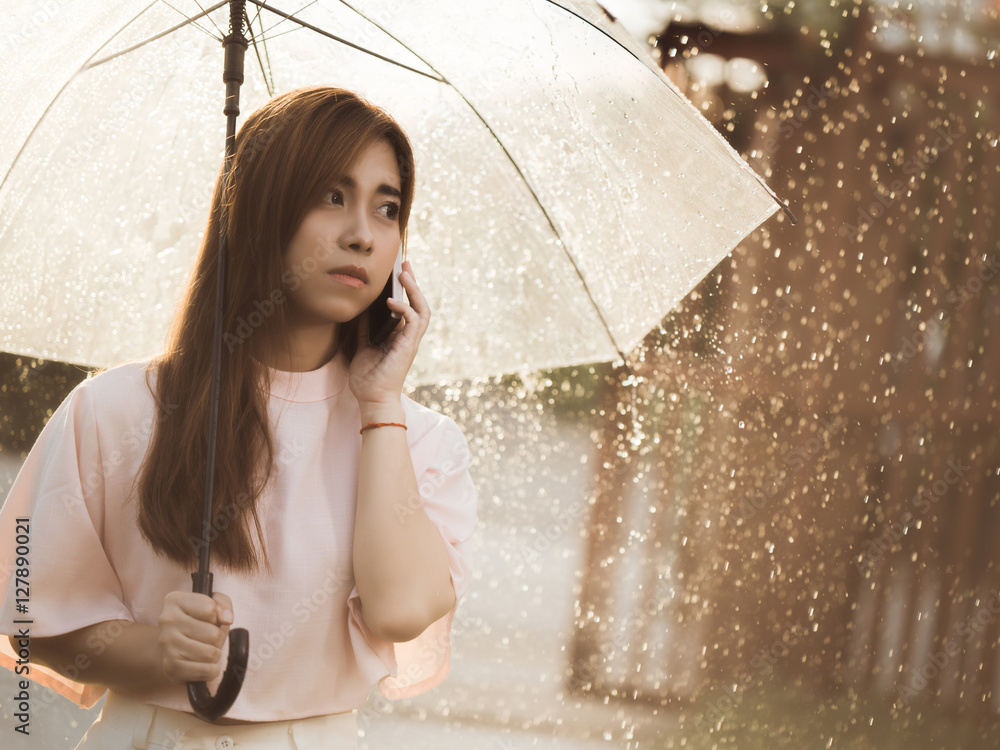 亚洲女人，她独自在雨中打电话。