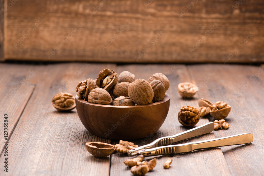 Walnuts in wooden bowl on table with Nutcracker.