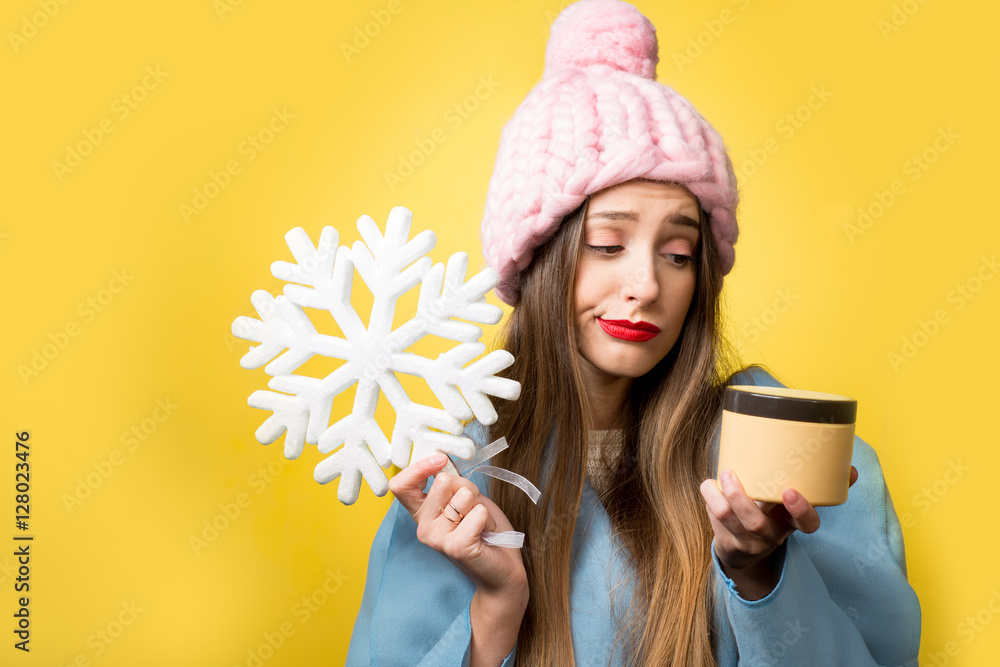 一个美丽女人的彩色冬季肖像，黄色背景上有面霜和雪花