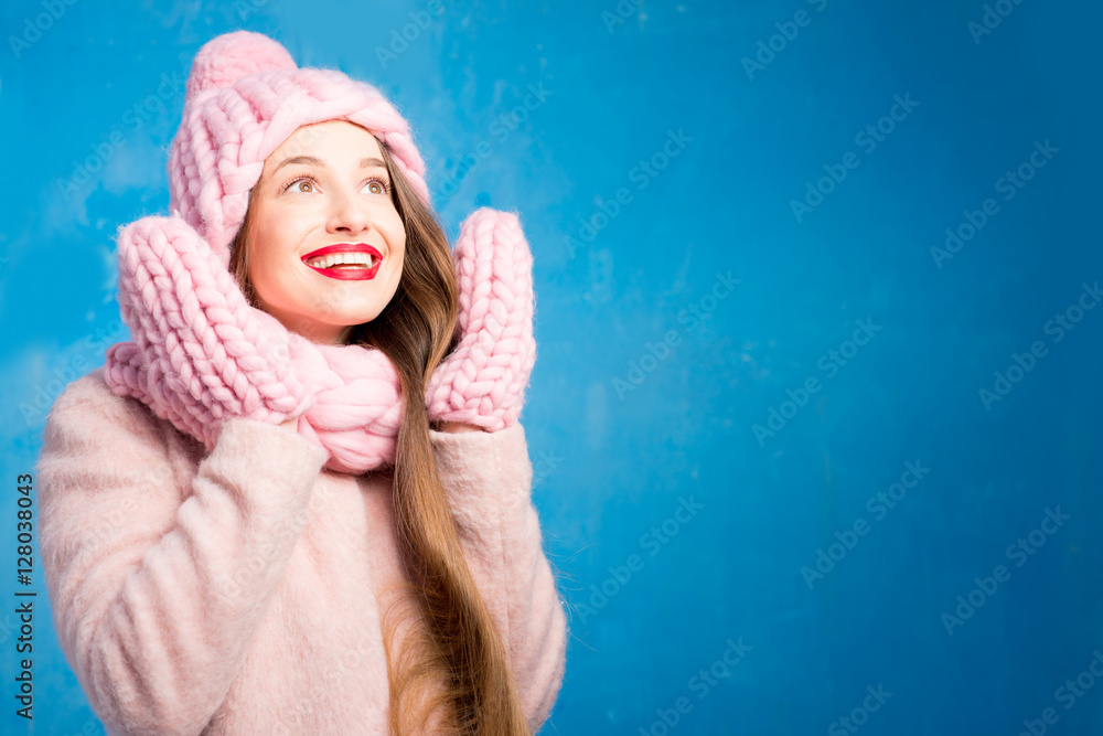 Winter portrait of a beautiful woman in knitted pink scurf, gloves and hat with snow flake on the bl