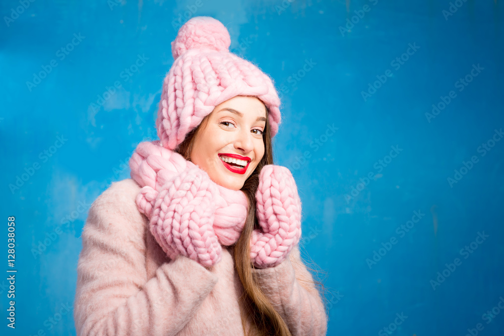 Winter portrait of a beautiful woman in knitted pink scurf, gloves and hat with snow flake on the bl