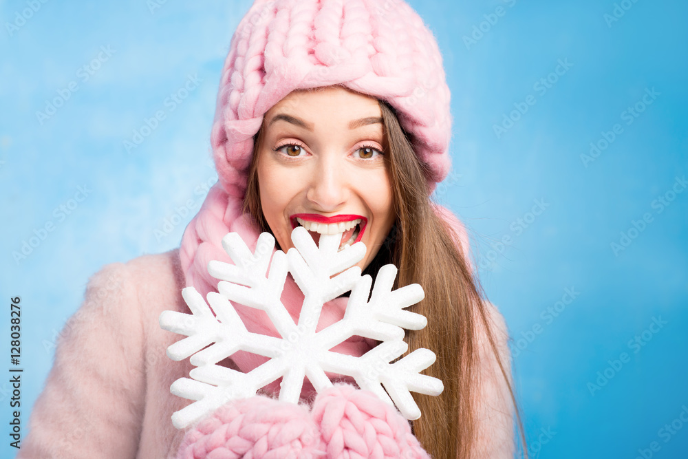 一位穿着针织粉色皮屑、手套和帽子的美女的冬季肖像，帽子上有雪花