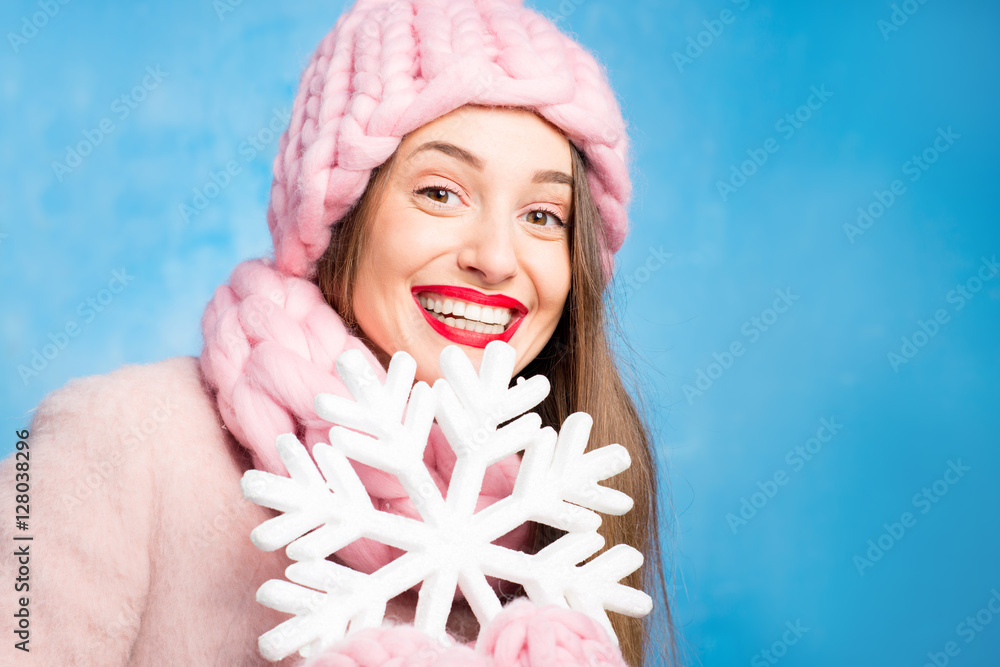 一位穿着针织粉色皮屑、手套和帽子的美女的冬季肖像，帽子上有雪花