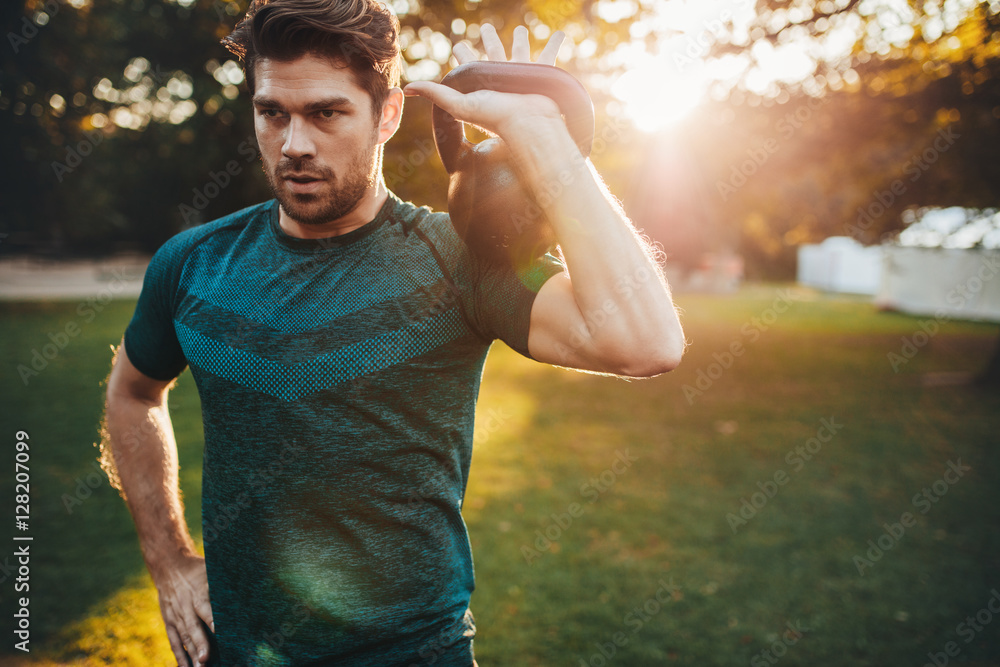 Fit young man exercising with kettlebell in park