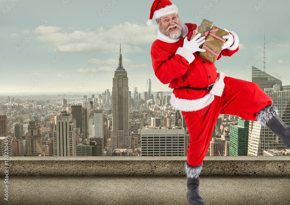 Santa claus  holding gift boxes standing on balcony of a buildin