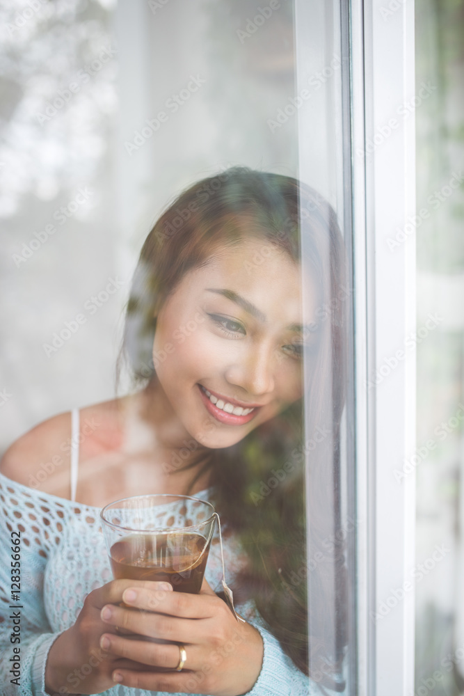 一位美丽的年轻亚洲女性与一杯ho一起放松的肖像