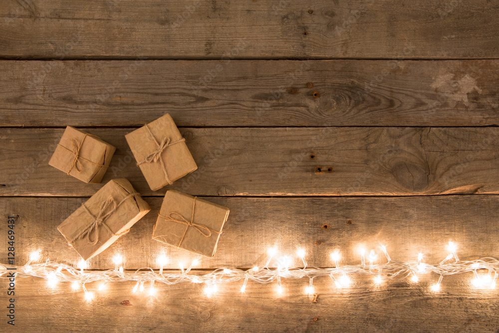 Christmas gift boxes and lights on the wooden background