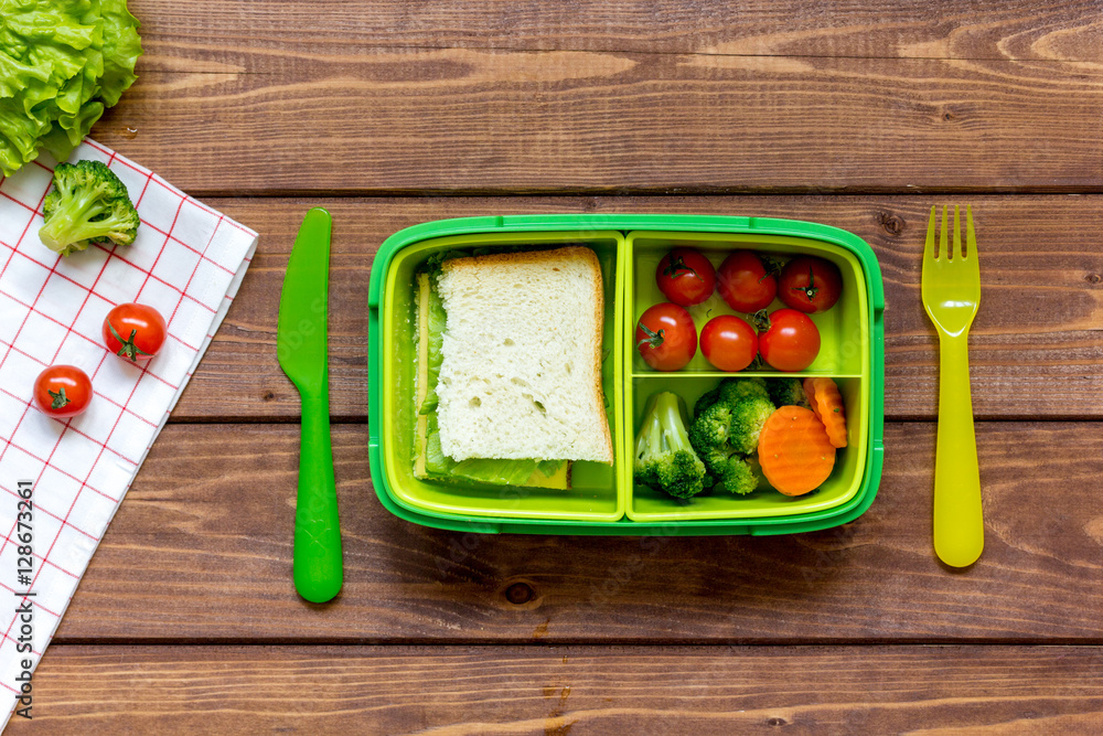 green lunch box for kid on wooden background top view