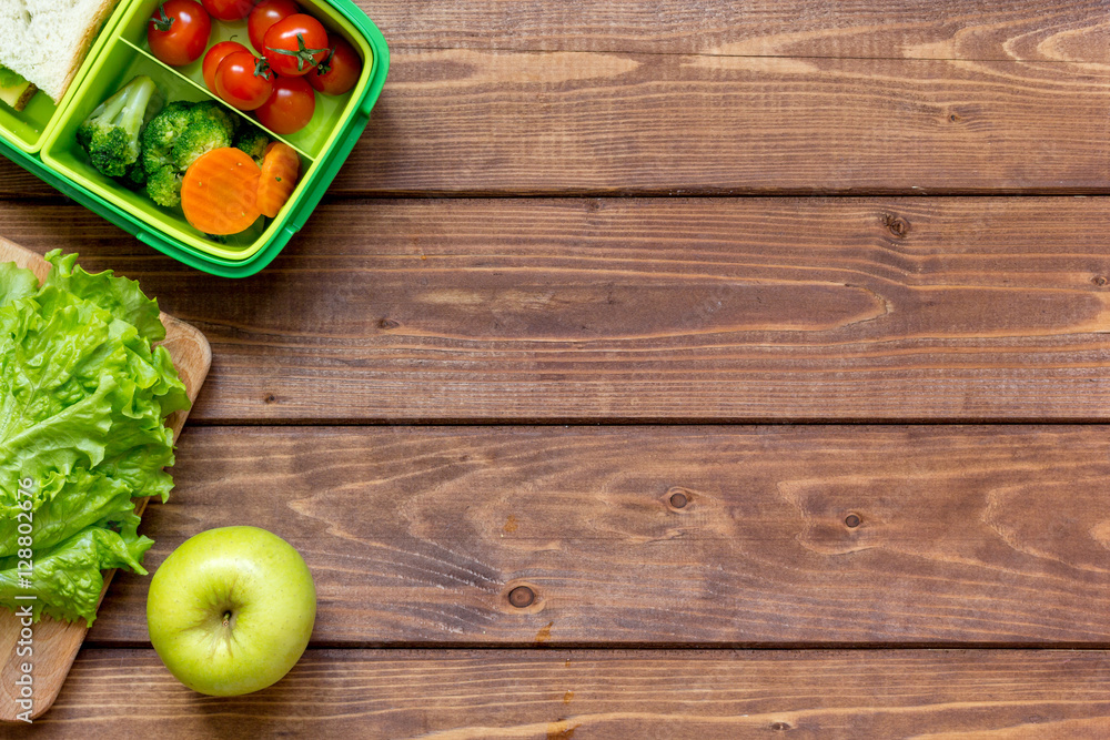 green lunch box for kid on wooden background top view